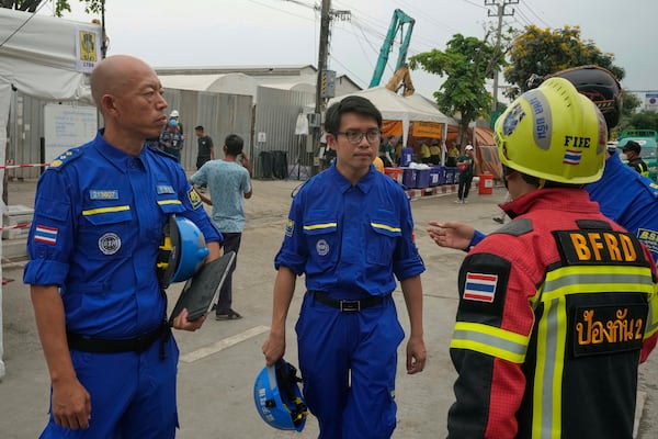 A Thai rescuer talks to members of the Blue Sky Rescue (BSR) team from China's Hunan province at the site of an under-construction high-rise building that collapsed after an earthquake in Bangkok, Thailand, Monday, March, 31, 2025. (AP Photo/Manish Swarup)