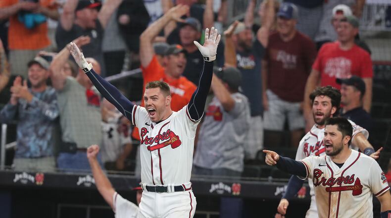 Braves first baseman Freddie Freeman (left) and catcher Travis d'Arnaud react from the dugout as second baseman Ozzie Albies hits a three-run walk-off homer for an 8-6 victory over the Cincinnati Reds during the 11th inning Wednesday night at Truist Park. The win moved the Braves into a tie for first place in the NL East. (Curtis.Compton@ajc.com)