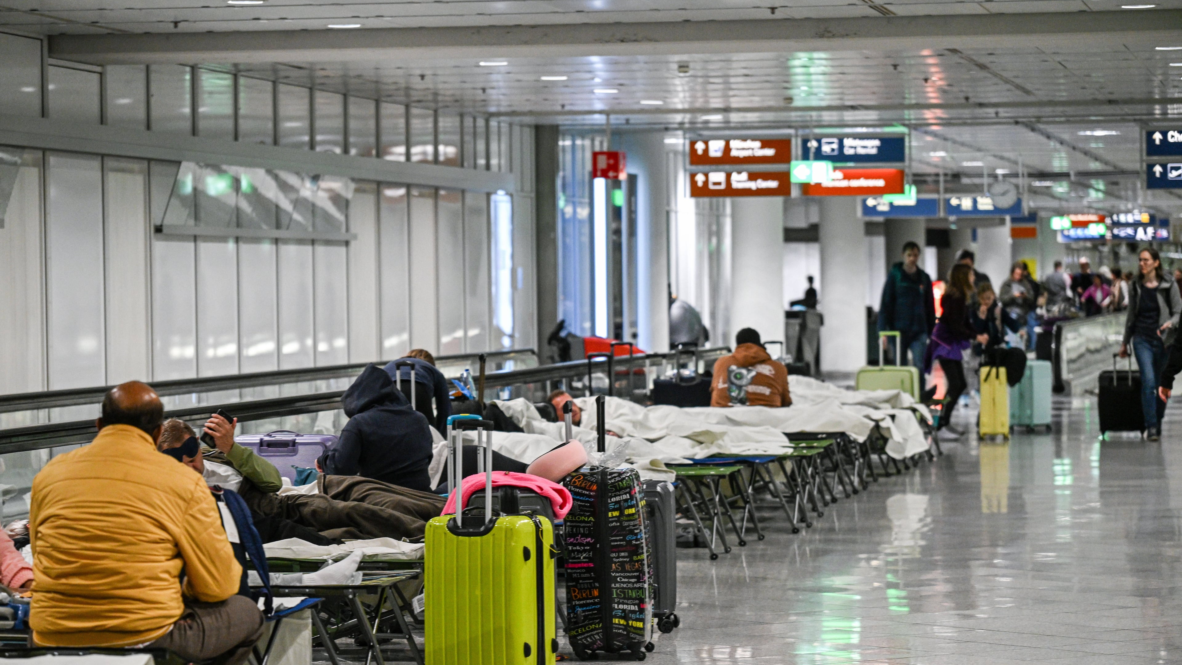 People wait on cots after drone sightings and flight cancellations at at Munich Airport, Friday, Oct.3, 2025. (Jason Tschepljakow/dpa via AP)