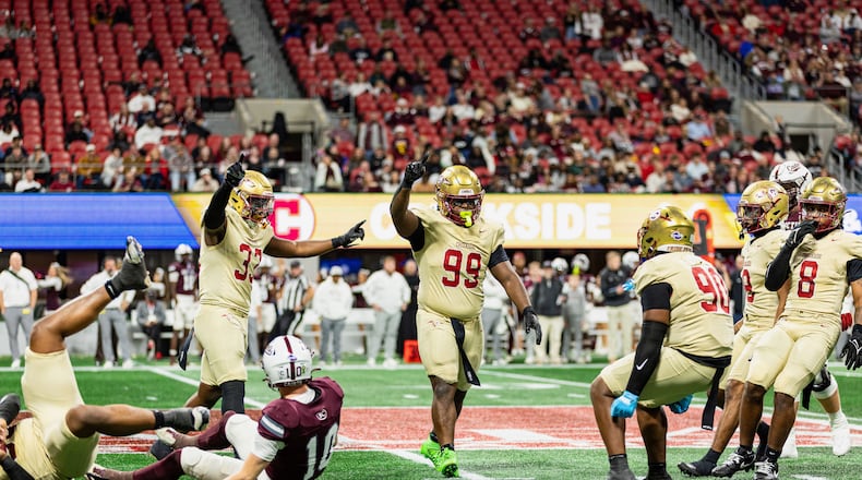 Creekside's Daniel Holt (right center, with blue gloves) celebrates with teammates Tavarre Terrell (left center, with two arms raised) and Cassius Burch (center, with one arm raised) during the GHSA Class 4A state championship game vs. Benedictine in December. The Seminoles won 42-39. (Courtesy of Cassius Burch and IQue Media Group)