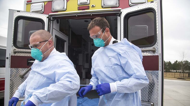 David Beranek (right), operation field supervisor at Metro Atlanta Ambulance Services, assists Anthony Zajac (left), clinical field supervisor at Metro Atlanta Ambulance Services, with his protective gear . (ALYSSA POINTER/ALYSSA.POINTER@AJC.COM)