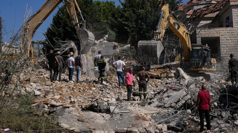 People watch rescue workers use excavators as they search for victims under the rubble of a building destroyed in an Israeli airstrike in the southern village of Kfar Rumman, Lebanon, Monday, Sept. 7, 2026. (AP Photo/Mohammed Zaatari)