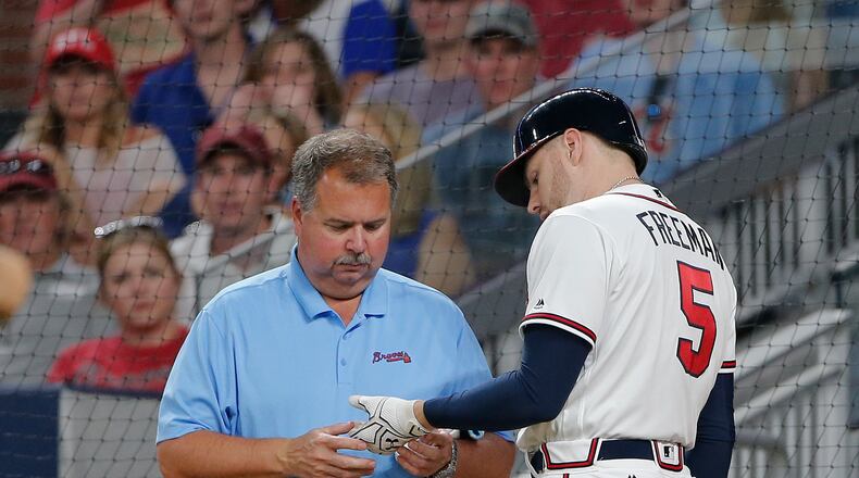 Braves athletic trainer Jim Lovell inspects Freddie Freeman's injury Wednesday night, but can't make it better. (AP Photo/John Bazemore)