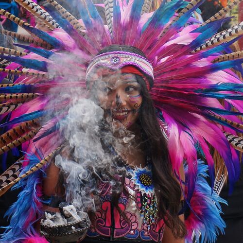 A member of an Aztec dance group holds incense during a commemoration of Día de Muertos (Day of the Dead) at El Colegio High School in Minneapolis on Saturday, Nov. 1, 2025. (AP Photo/Giovanna Dell'Orto)