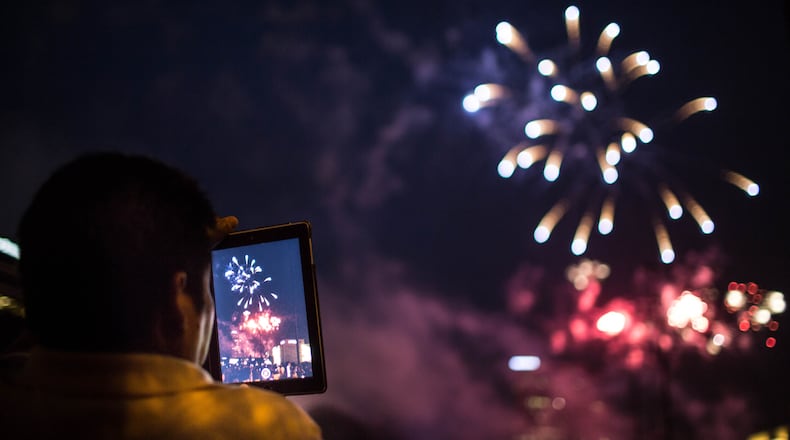 A man records a fireworks show on his iPad at Lenox Square during the annual July 4th event in 2015.