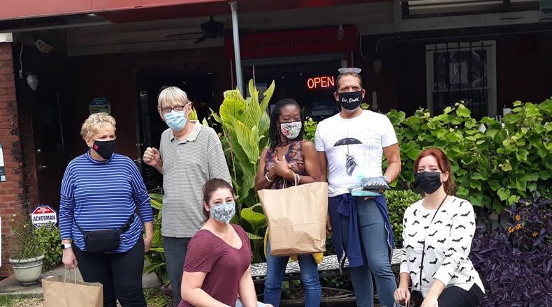 Six people wearing face masks pose holding paper bags in front of Babs restaurant.