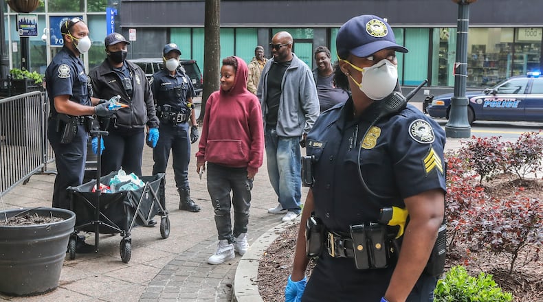 April 24, 2020 Atlanta: Atlanta police Sgt. Dominique Simmons (right) and her team of officers distribute masks to the homeless at Woodruff Park on Friday, April 24, 2020 in downtown Atlanta. Atlanta police Sgt. Dominique Simmons has taken the personal initiative to get masks to some of the homeless population in Atlanta. Simmons who has been on the streets twice since last Friday has been distributing masks where many of the cityâs homeless congregate in downtown. Gaining permission from her Zone 6 superiors she and other fellow officers were given the go-ahead for the idea. A mother of the Sergantâs brotherâs girlfriend in Texas made 270 masks and sent them to Sgt. Simmons who asked for them. As of Friday they are all gone, but she has asked for more. JOHN SPINK/JSPINK@AJC.COM