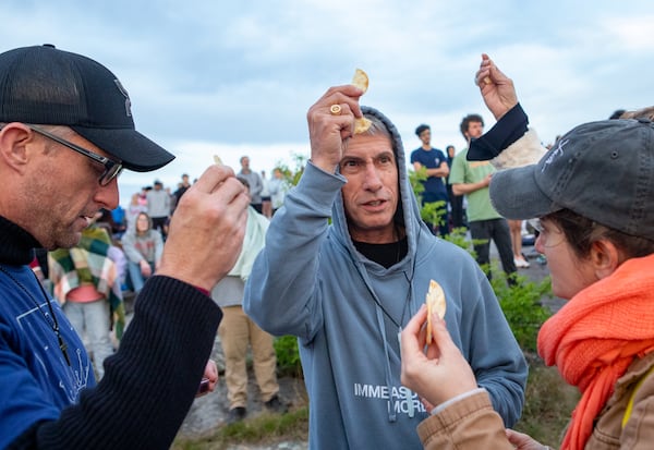 Jared Pennisi (from left) Daniel Flagg and Viola Boraros take communion during the Easter Sunrise Service atop Stone Mountain on Sunday, April 20, 2025. (Jenni Girtman for The Atlanta Journal-Constitution)