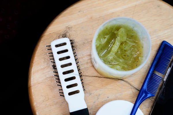 Braiding grease is seen next to a brush and comb at Eve's African Braiding in College Park, Ga., Tuesday, May 6, 2025. (AP Photo/Stephanie Scarbrough)