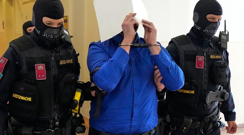 Defendant Beran A. is hiding his face behind file folders when he is escorted out of the courtroom in the District Court in Wiener Neustadt, Austria, where he stands trial for plotting to carry out an attack on one of superstar singer Taylor Swift's concerts in Vienna in August 2024 and pledging allegiance to the Islamic State group, Tuesday, April 28, 2026. (AP Photo/Matthias Schrader)