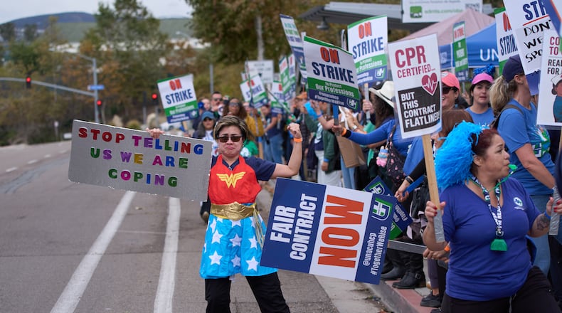Kaiser Permanente health care workers hold signs and chant slogans while on strike in front of the Kaiser Permanente San Diego Medical Center Tuesday, Oct. 14, 2025, in San Diego. (AP Photo/Gregory Bull)