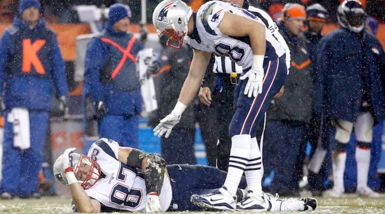 New England Patriots tight end Rob Gronkowski (87) lies injured on the field against the Denver Broncos as teammate tight end Scott Chandler (88) trees to help him up during the second half of an NFL football game, Sunday, Nov. 29, 2015, in Denver. (AP Photo/Joe Mahoney)