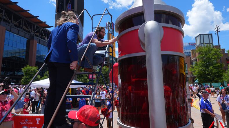 Eric Johnson and Guinness World Records adjudicator Thomas Bradford check the level of beer before certifying a world record for Largest Glass of Beer ahead of a baseball game between the Detroit Tigers and Texas Rangers, Saturday, July 4, 2026, in Arlington, Texas. (AP Photo/LM Otero)