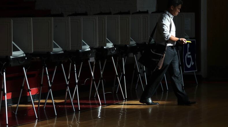 Sunlight streams through the windows of the gym as a voter walks away from the voting booths after voting during the Georgia runoff election voting at Henry W. Grady High School on July 24 in Atlanta. (JASON GETZ/SPECIAL TO THE AJC)