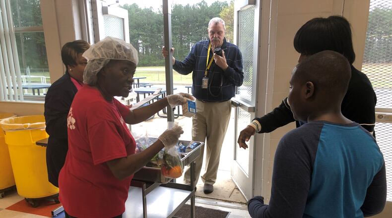 Zeborah Ogletree on Monday hands food to Jordan Woods and his mother Kenyatta Veasey at North Clayton Middle School.
