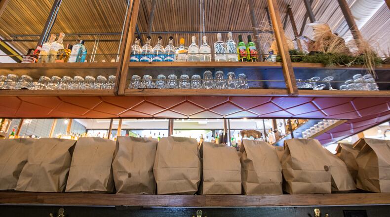 The bar at Superica on Roswell Road holds 4 times as many to-go bagged chips and salsa as a month ago.  The staff preps food in take-out containers and continues to serve drive-up customers with limited contact.  Half of the Rocket Farm Restaurants in Atlanta are completely closed and wait staff has been laid off.  (Jenni Girtman for the Atlanta Journal Constitution)