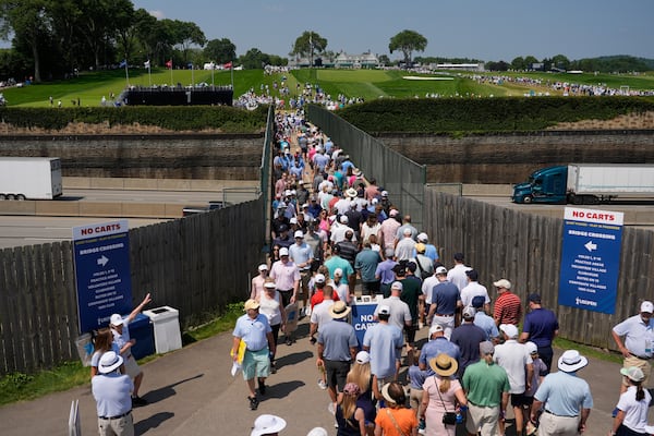 Fans use a pedestrian bridge over the Pennsylvania Turnpike, which divides Oakmont Country Club, during a practice round ahead of the U.S. Open golf tournament Wednesday, June 11, 2025, in Oakmont, Pa. (AP Photo/Carolyn Kaster)