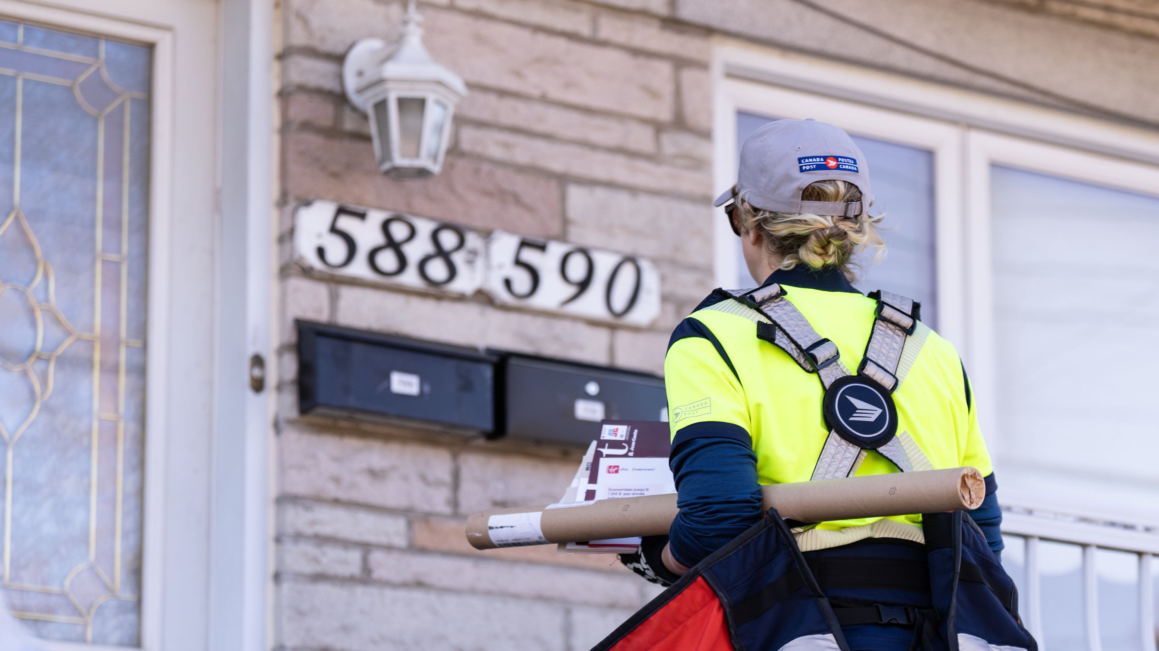 FILE - A Canada Post mail carrier delivers mail and packages on their route in Montreal, Wednesday, Nov. 13, 2024. (Christinne Muschi/The Canadian Press via AP, File)