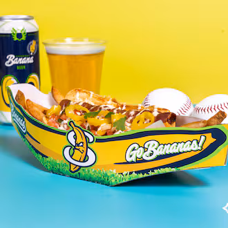 A loaded hot dog in a Savannah Bananas vessel is flanked by a couple of baseballs and a beer.