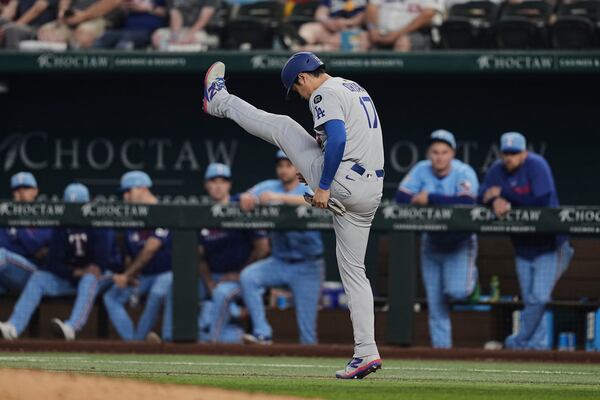Los Angeles Dodgers' Shohei Ohtani stretches as he walks to first after earning a walk in the eighth inning of a baseball game against the Texas Rangers in Arlington, Texas, Sunday, April 20, 2025. (AP Photo/Tony Gutierrez)