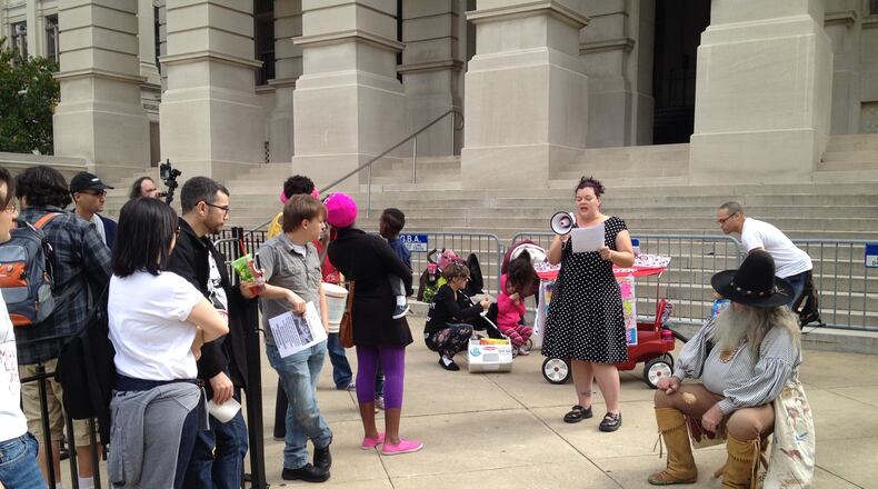 Caroline Holko of Marietta uses a bullhorn to address protesters gathered at the state Capitol on Saturday for the March Against Corruption. Aaron Gould Sheinin/AJC