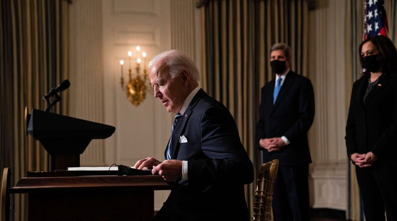 President Joe Biden signs an executive order regarding his administration's response to climate change, in the State Dining Room of the White House in Washington, Wednesday, Jan. 27, 2021. John Kerry, the global envoy for climate change, and Vice President Kamala Harris look on. (Anna Moneymaker/The New York Times)