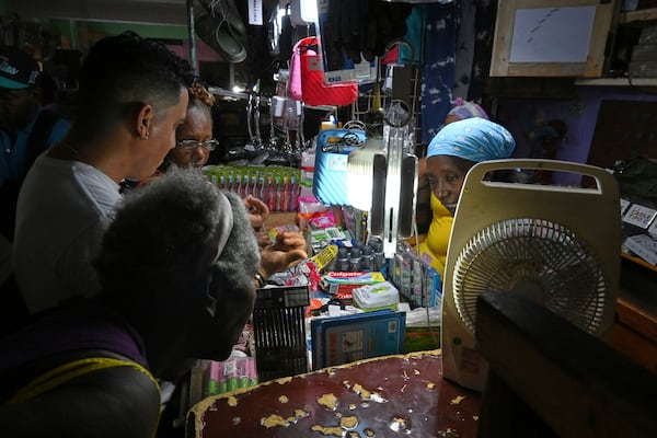 A merchant uses rechargeable lamps for illumination while serving customers during a power outage, inside a private hardware market, in Havana, Cuba, Tuesday, July 15, 2025. (AP Photo/Jorge Luis Baños)