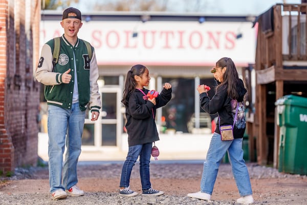 Tour guide Cannon Dail encourages Isabella Campos, 10, and her 7-year-old sister, Audrey, to reenact the alley fight scene from "Stranger Things." (Jason Allen for the AJC)