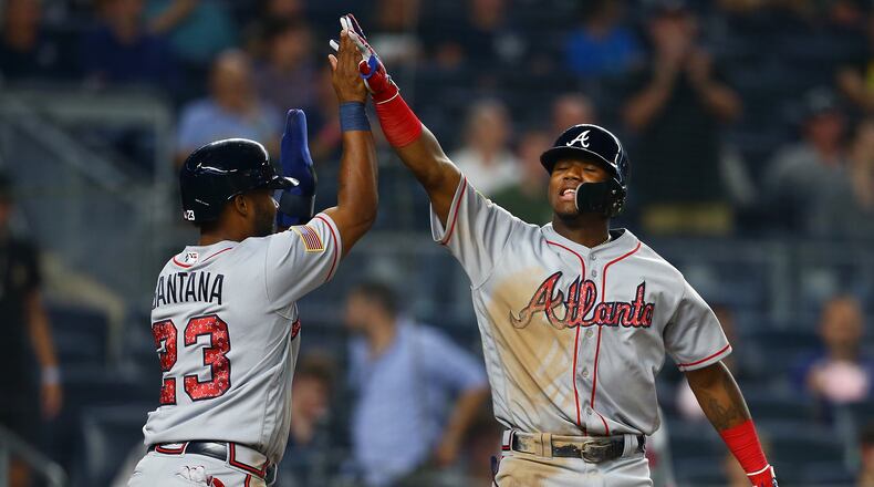 Ronald Acuna celebrates with Danny Santana after hitting a two-run homer in the 11th inning of Monday's 5-3 win over the Yankees in New York. (Photo by Mike Stobe/Getty Images)