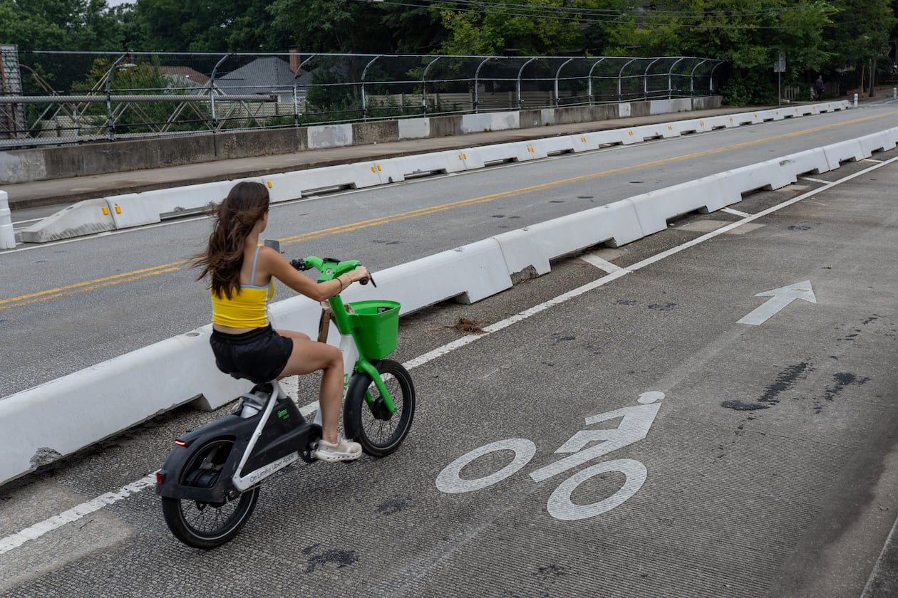 A woman rides a bicycle inside the protected bike lane along Cherokee Street on Thursday, July 30, 2026. (Ben Hendren for the AJC)