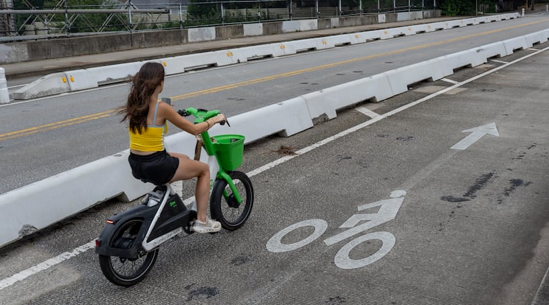 A woman rides a bicycle inside the protected bike lane along Cherokee Street on Thursday, July 30, 2026. (Ben Hendren for the AJC)