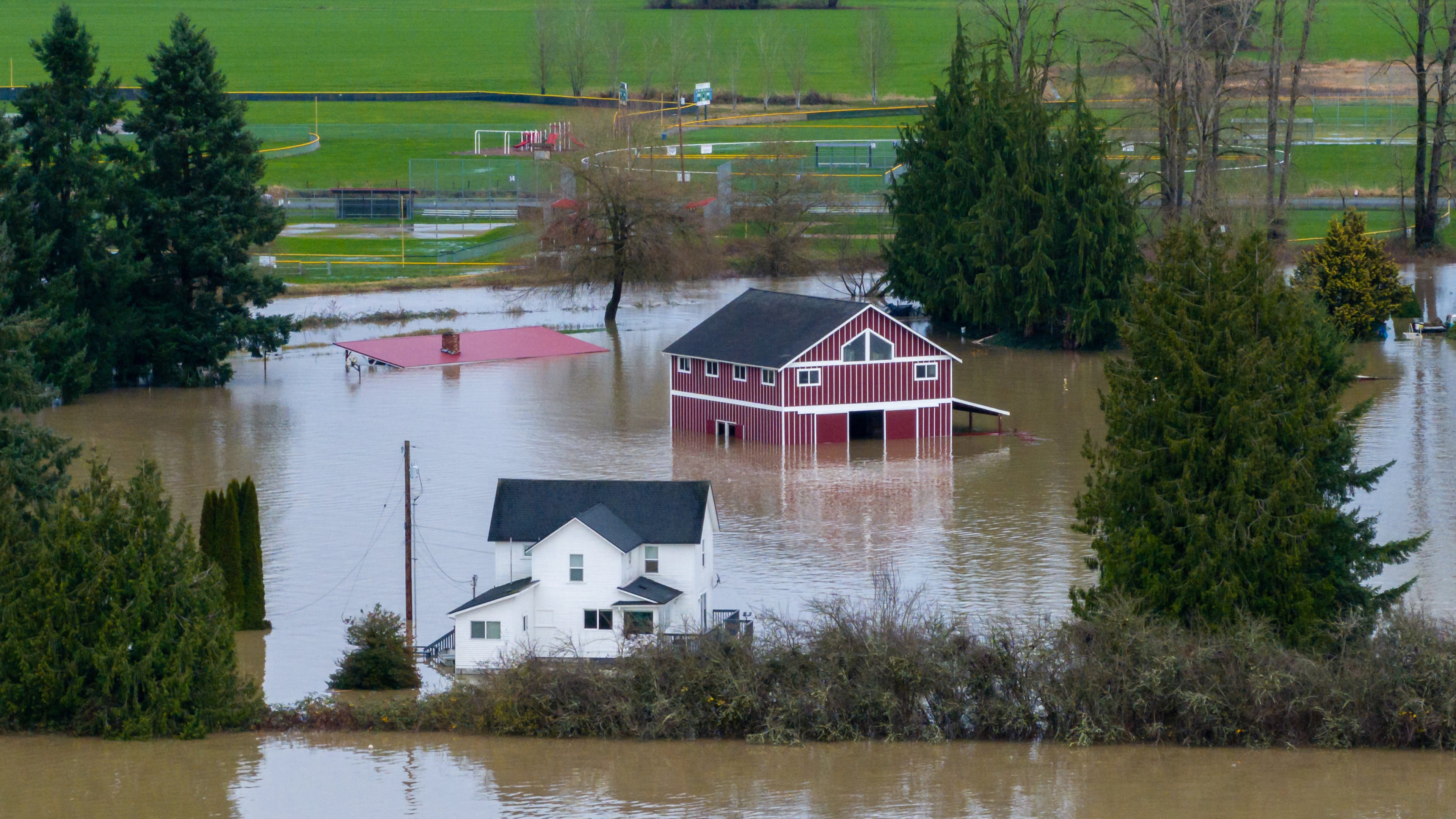 A n aerial view of a home and a barn surrounded by floodwaters in Snohomish, Wash., Thursday, Dec. 11, 2025. (AP Photo/Stephen Brashear)
