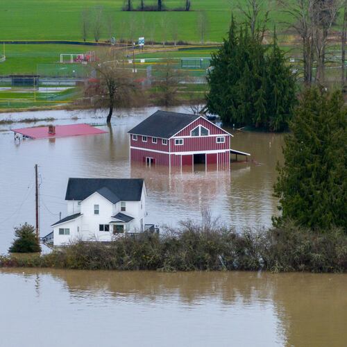 A n aerial view of a home and a barn surrounded by floodwaters in Snohomish, Wash., Thursday, Dec. 11, 2025. (AP Photo/Stephen Brashear)