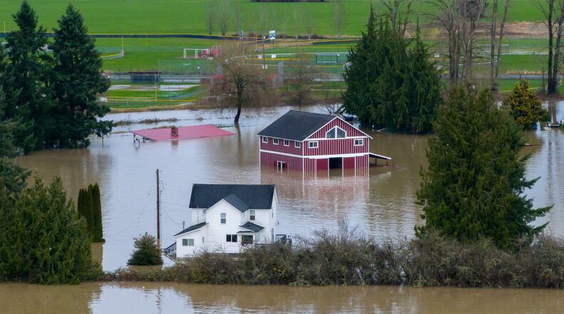 A n aerial view of a home and a barn surrounded by floodwaters in Snohomish, Wash., Thursday, Dec. 11, 2025. (AP Photo/Stephen Brashear)