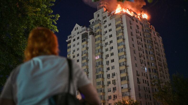 A woman looks at an apartment building burning after a Russian missile attack in Kyiv, Ukraine, Thursday, July 2, 2026. (AP Photo/Danylo Antoniuk)