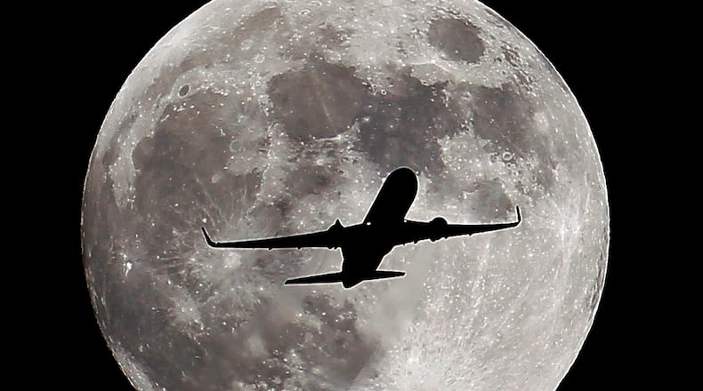 A passenger airliner crosses the full moon, also known as the Hunter's Moon, in Whittier, Calif., on Oct. 7, 2014. (AP Photo/ Nick Ut )