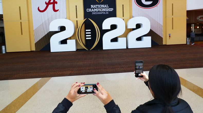 010722 Indianapolis: Football fans Diana Trujillo (left) and Jasmyn Lecompte snap a photo of the main display at the entrance to the Playoff Fan Central inside Indianopolis Convention Center on Friday, Jan. 7, 2022, in Indianapolis. Georgia will play Alabama for the national championship title next door at Lucas Oil Stadium on Monday. “Curtis Compton / Curtis.Compton@ajc.com”`