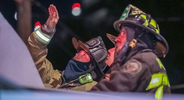Atlanta firefighters (from left) Shane Bell, Matt Boehner and Yahya Azhari endure the early Tuesday morning cold on 12th Street while working the scene of a building fire.