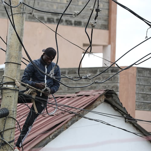 A man connects electric cables on a pole above the Kibera informal settlement in Nairobi, Kenya, Tuesday, March 31, 2026. (AP Photo/Henry Naminde)