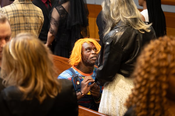 Jonathan Morehead, dressed as Chucky, gives a ring to Peaches Morehead during their Halloween marriage ceremony. (Arvin Temkar/AJC)