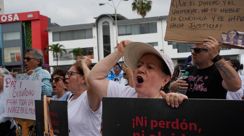 Protesters hold banners outside the courthouse where soldiers were sentenced for the disappearance and killing of four children who went missing in December 2024, in Guayaquil, Ecuador, Monday, Dec. 22, 2025. (AP Photo/Cesar Munoz)