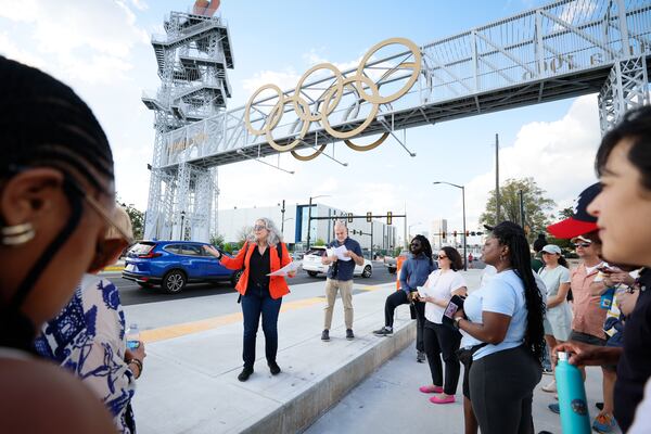 Georgia State University associate professor Marni Davis (center) speaks to community members beneath the Atlanta Olympic Cauldron Tower during a tour of the Summerhill neighborhood on Tuesday, March 31, 2026. (Miguel Martinez/AJC)