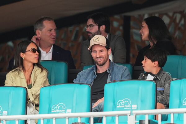 Soccer star Lionel Messi, center, sits with his wife Antonela Roccuzzo, left, and their three sons, one of whom is seen at right, as they watch a semifinal match between Novak Djokovic, of Serbia, and Grigor Dimitrov, of Bulgaria, at the Miami Open tennis tournament, Friday, March 28, 2025, in Miami Gardens, Fla. (AP Photo/Rebecca Blackwell)