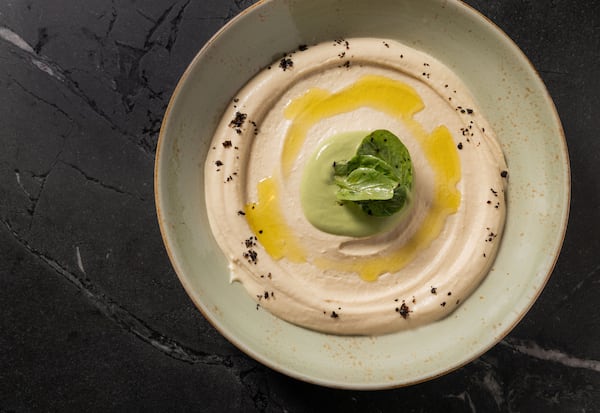 Rumi's Kitchen hummus is garnished with a spoonful of tahini blended with jalapeno and herbs, drizzled with olive oil, sprinkled with Urfa chiles and topped with leaves of watercress. (Courtesy of Rumi's Kitchen)