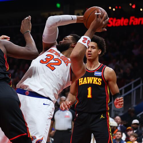 New York Knicks center Karl-Anthony Towns (32) rebounds against Atlanta Hawks forwards Onyeka Okongwu (17) and Jalen Johnson (1) during the second half of an NBA basketball game, Monday, April 6, 2026, in Atlanta. (AP Photo/Colin Hubbard)