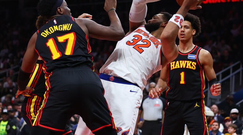 New York Knicks center Karl-Anthony Towns (32) rebounds against Atlanta Hawks forwards Onyeka Okongwu (17) and Jalen Johnson (1) during the second half of an NBA basketball game, Monday, April 6, 2026, in Atlanta. (AP Photo/Colin Hubbard)