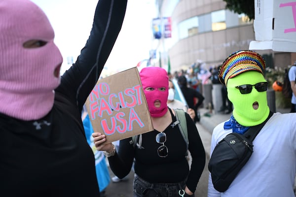 Demonstrators wearing masks hold signs outside the Federal Building during a protest on Friday, June 13, 2025, in Los Angeles. (AP Photo/Wally Skalij)