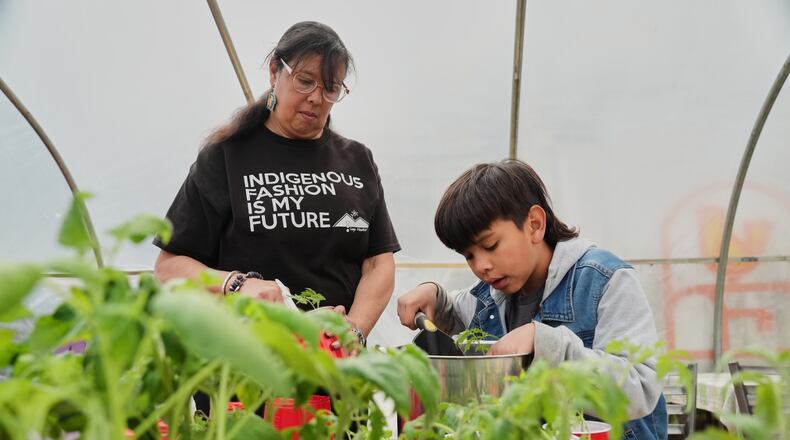 Dawn Spears, left, and her grandson, Giizhig, 9, right, prepare tomatoes for planting Tuesday, April 21, 2026, at a farm in Hopkinton, R.I. (AP Photo/Joshua A. Bickel)