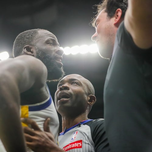 Golden State Warriors forward Draymond Green (23) is held back by referee Courtney Kirkland while talking to New Orleans Pelicans fan Sam Green during the first half of an NBA basketball game against the New Orleans Pelicans in New Orleans, Sunday, Nov. 16, 2025. (David Grunfeld/The Times-Picayune via AP)