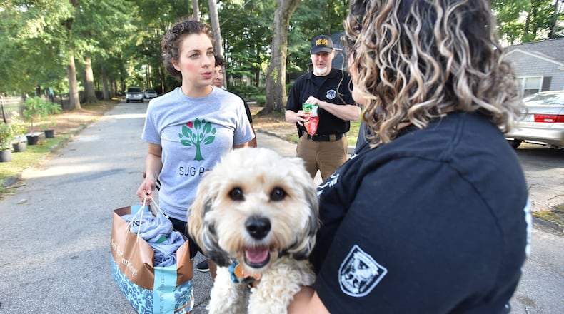 Sofia Bork (left) greets Lizandra Mora (foreground), fiancee of fallen police officer Edgar Flores, as she holds Edgar Flores’s dog Sammy at Sara J. Gonzalez Memorial Park on Saturday, June 22, 2019. HYOSUB SHIN / HSHIN@AJC.COM